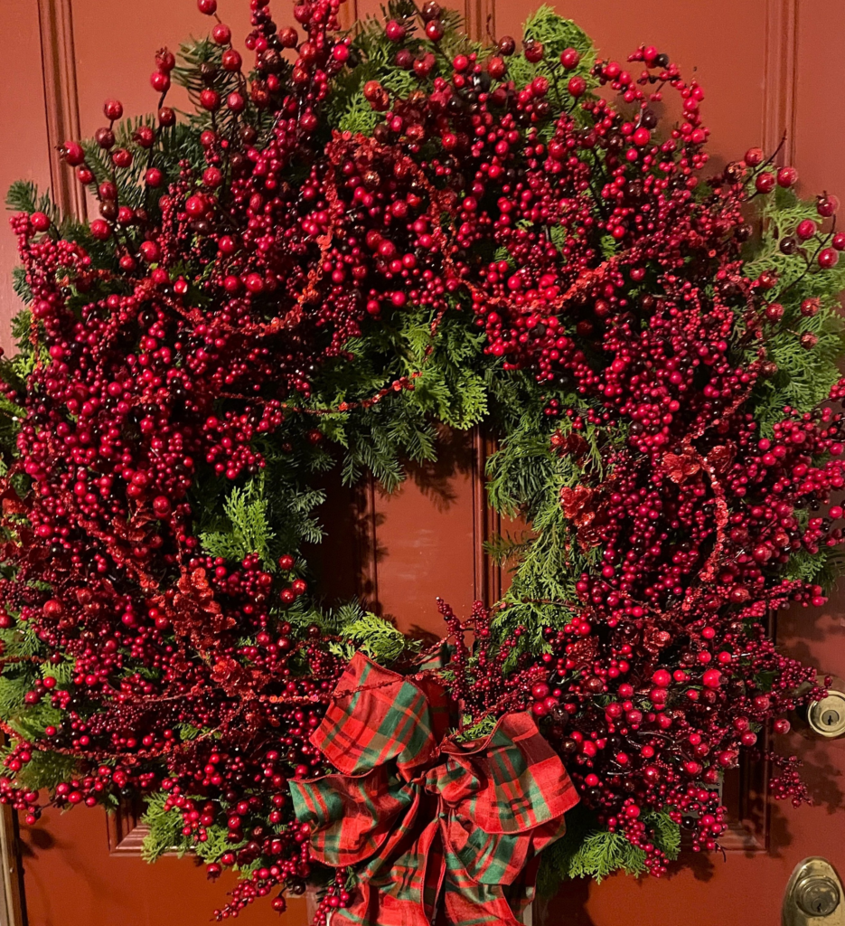 Handcrafted Red Berry holiday wreath featuring abundant winter berries, fresh evergreens, and a classic tartan bow.