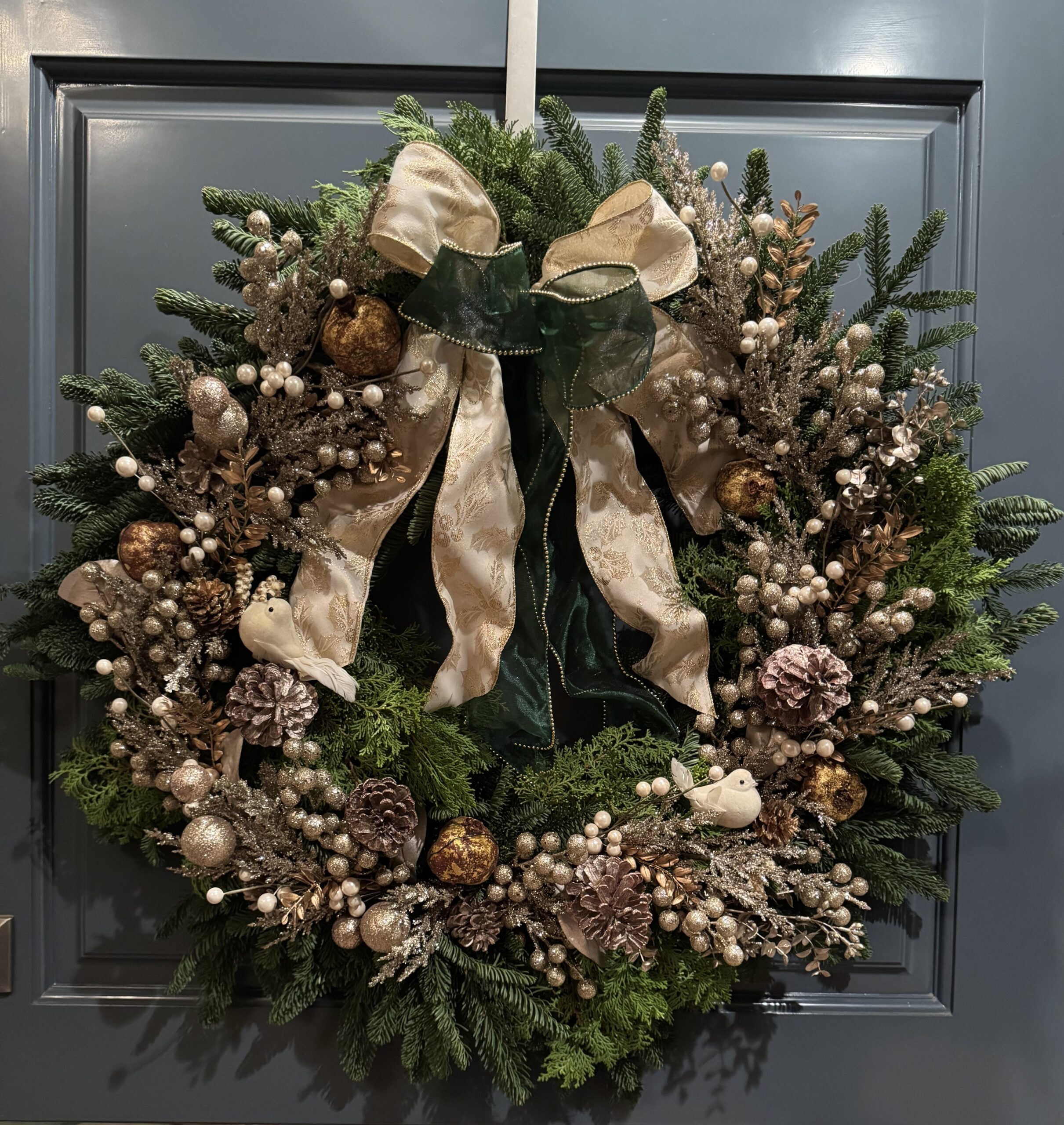 Handcrafted luxury holiday wreath displayed on a welcoming front door.